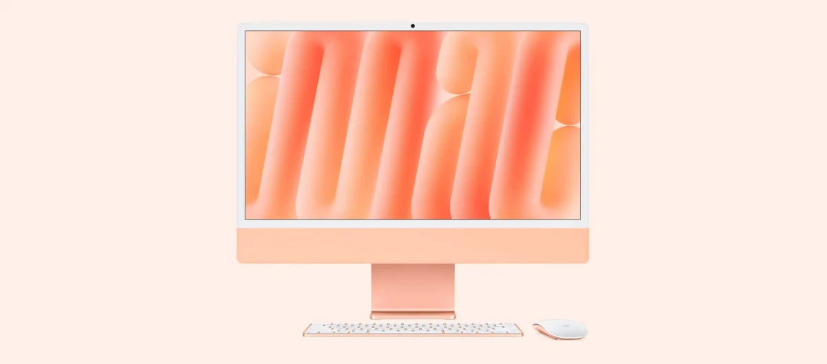Apple iMac: iMac laranja de frente sobre fundo rosa claro, com teclado e mouse brancos ao lado, tela com papel de parede laranja.