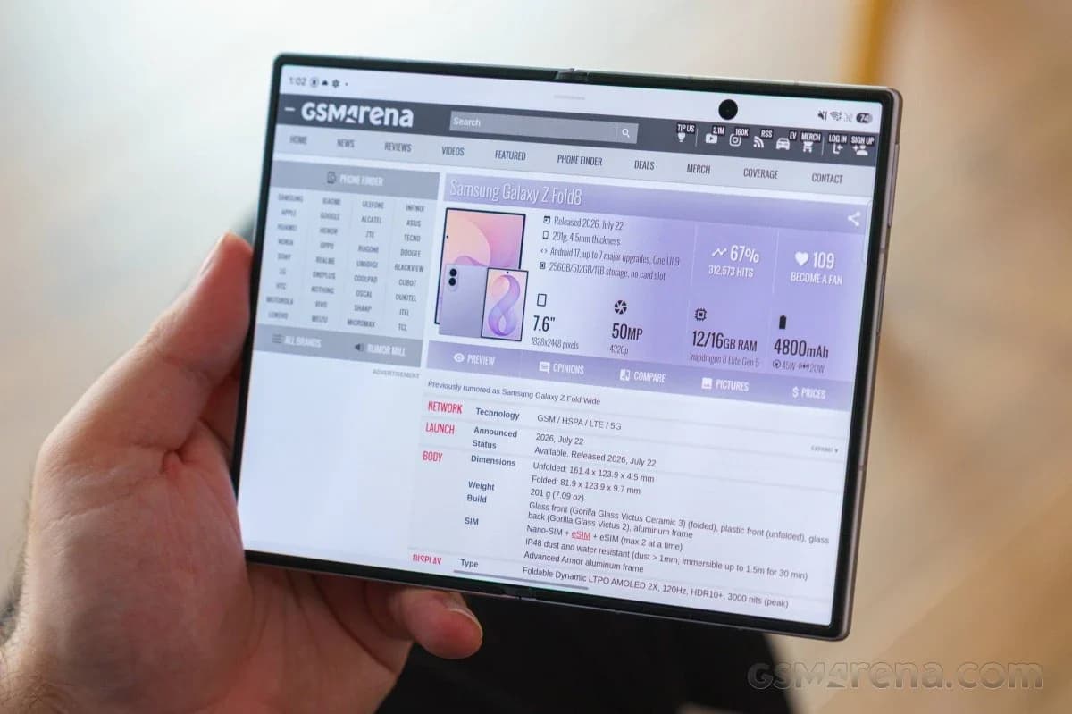 Samsung Galaxy Z Fold 8: Mão segurando celular dobrável aberto, com tela exibindo página de especificações em roxo e cinza.