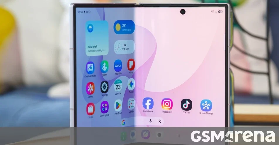 Samsung Galaxy Z Fold 8: Tela interna de smartphone dobrável aberto, de frente, com ícones de aplicativos e widgets de clima e relógio na tela inicial.