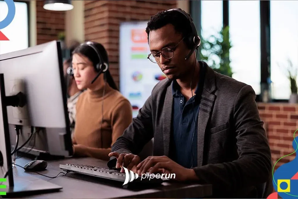 piperun Serviço de Atendimento ao Consumidor (SAC): Homem de óculos e fone de ouvido digitando em teclado diante do computador, com colega ao fundo; logo piperu