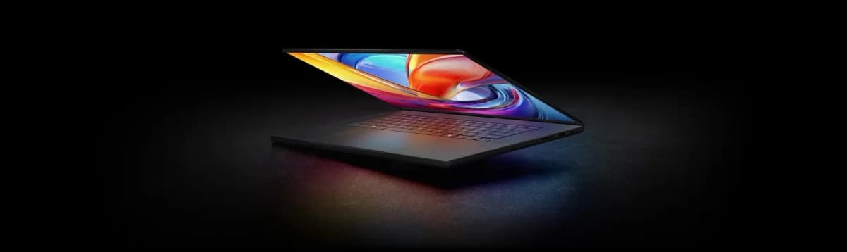 Asus ProArt P16: Notebook preto aberto em fundo escuro, com tela colorida e abstrata de cores quentes e frias, vista em ângulo lateral