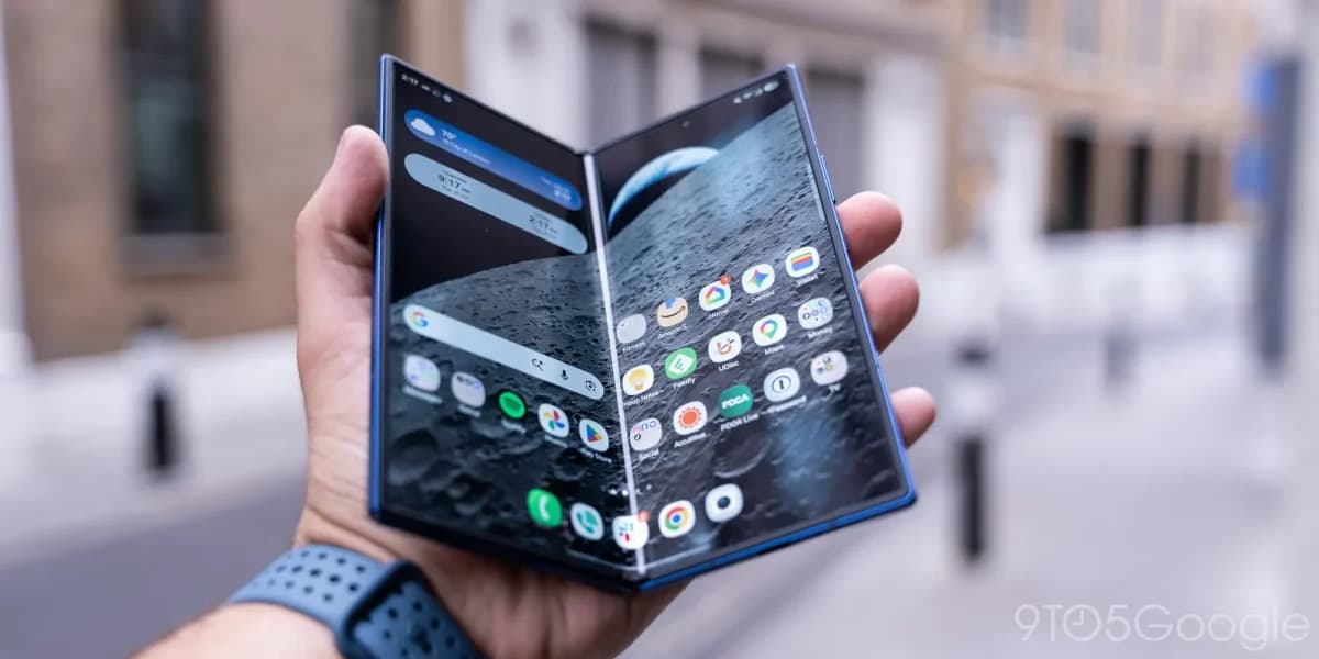 Samsung Galaxy Z Fold 7: Celular dobrável azul aberto, segurado por uma mão com pulseira azul, mostrando a tela interna com papel de parede lunar e ícones de ap