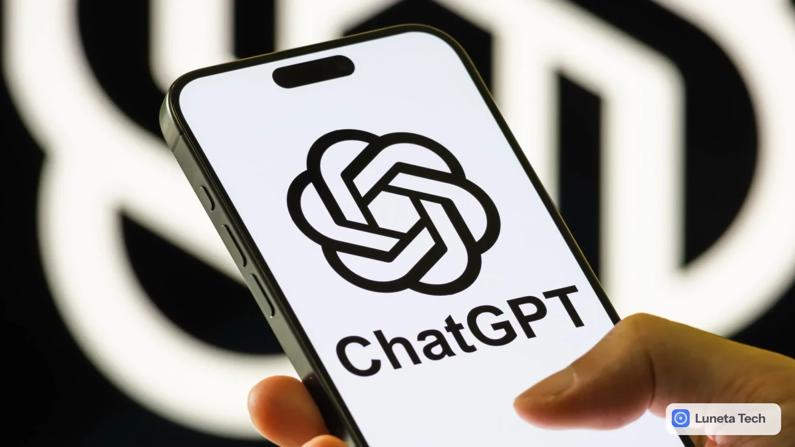 OpenAI GPT-6: Mão segurando um smartphone com a tela branca exibindo o logotipo e o nome ChatGPT, com logotipo grande em fundo escuro desfocado