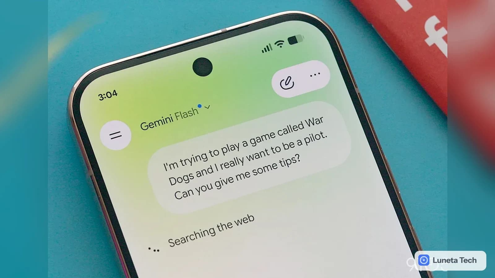 Google Google AI Plus, plano de assinatura do Gemini: Celular na diagonal, com a tela do app Gemini Flash aberta sobre fundo azul-turquesa e uma capa vermelha a