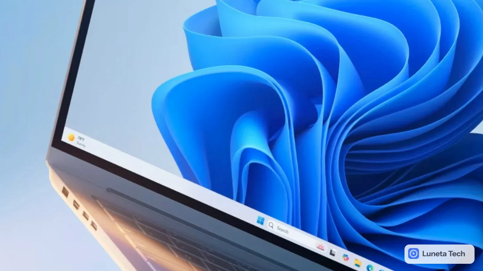 Microsoft Windows 11 atualização de desempenho gestão de memória: Close da tela de um notebook prateado, com papel de parede azul em formato de ondas e barra de