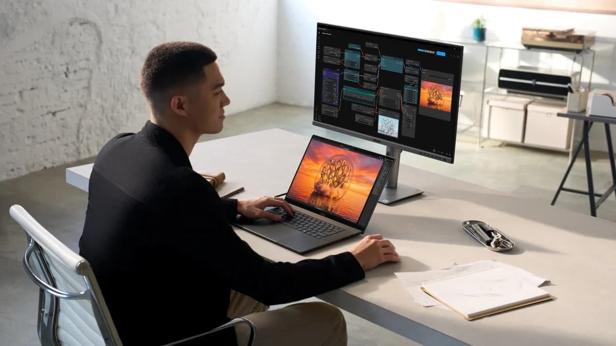 Asus ProArt P16: Homem de camisa preta usando notebook prateado sobre mesa clara, com monitor grande ao fundo.