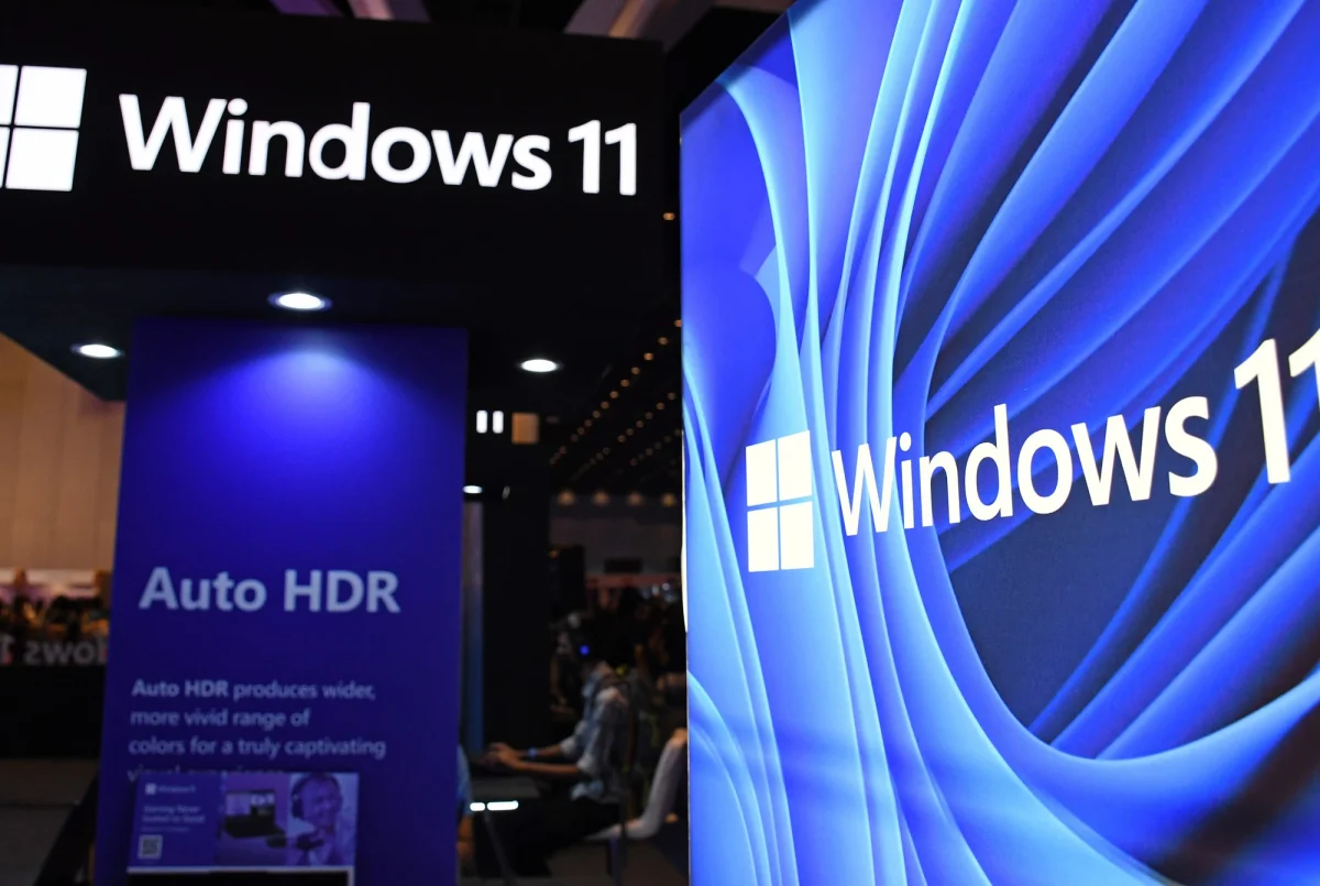 Microsoft Windows 11 atualização de desempenho gestão de memória: Estande de evento com placas pretas e azuis do Windows 11, logotipo branco e painel com o text